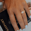 A womans hand with silicone rings on one finger and her hand is holding a passport